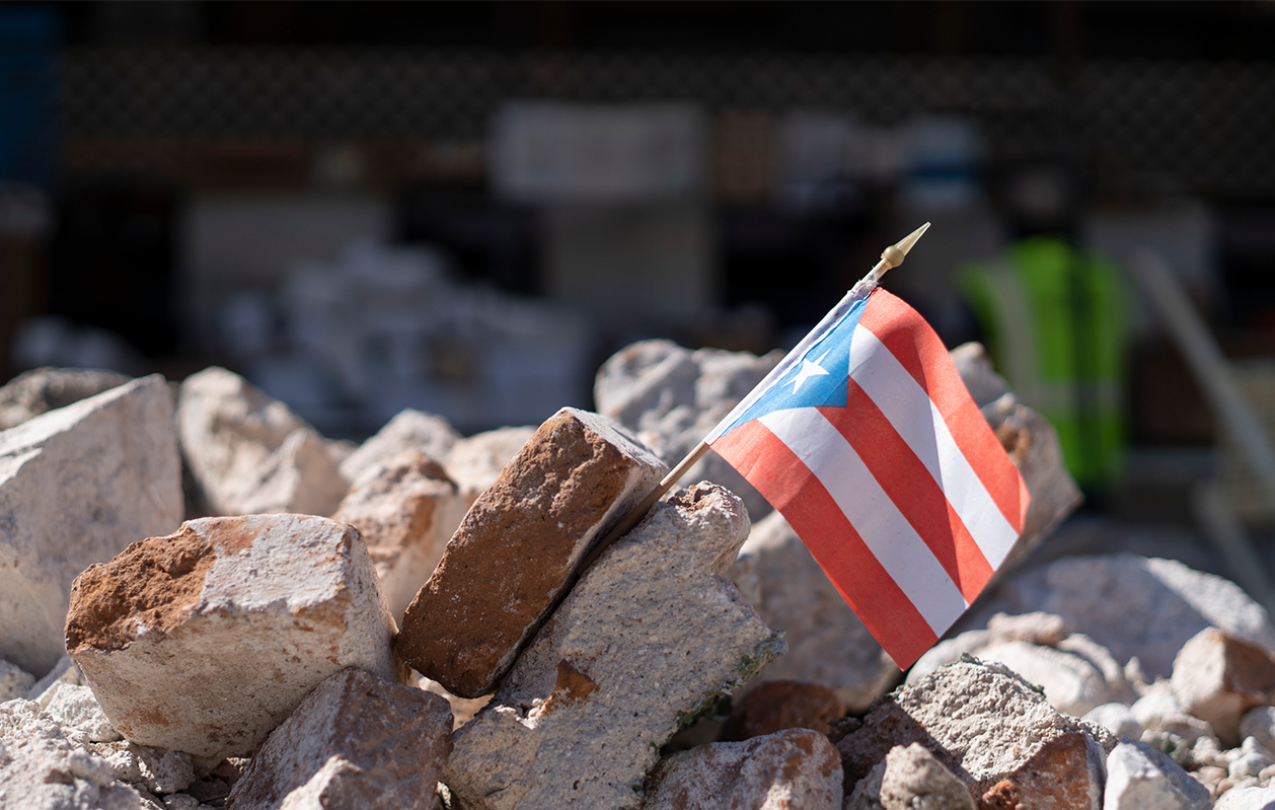 A Puerto Rican flag sits between stone rubble.